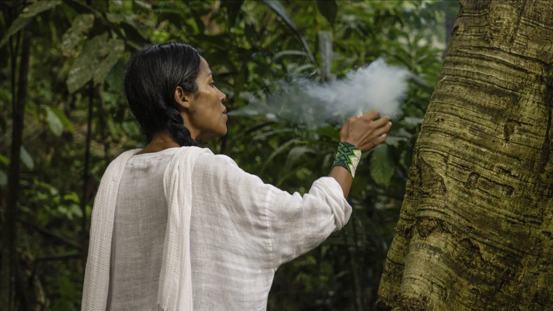 Tatiana blowing smoke at a tree in the rainforest